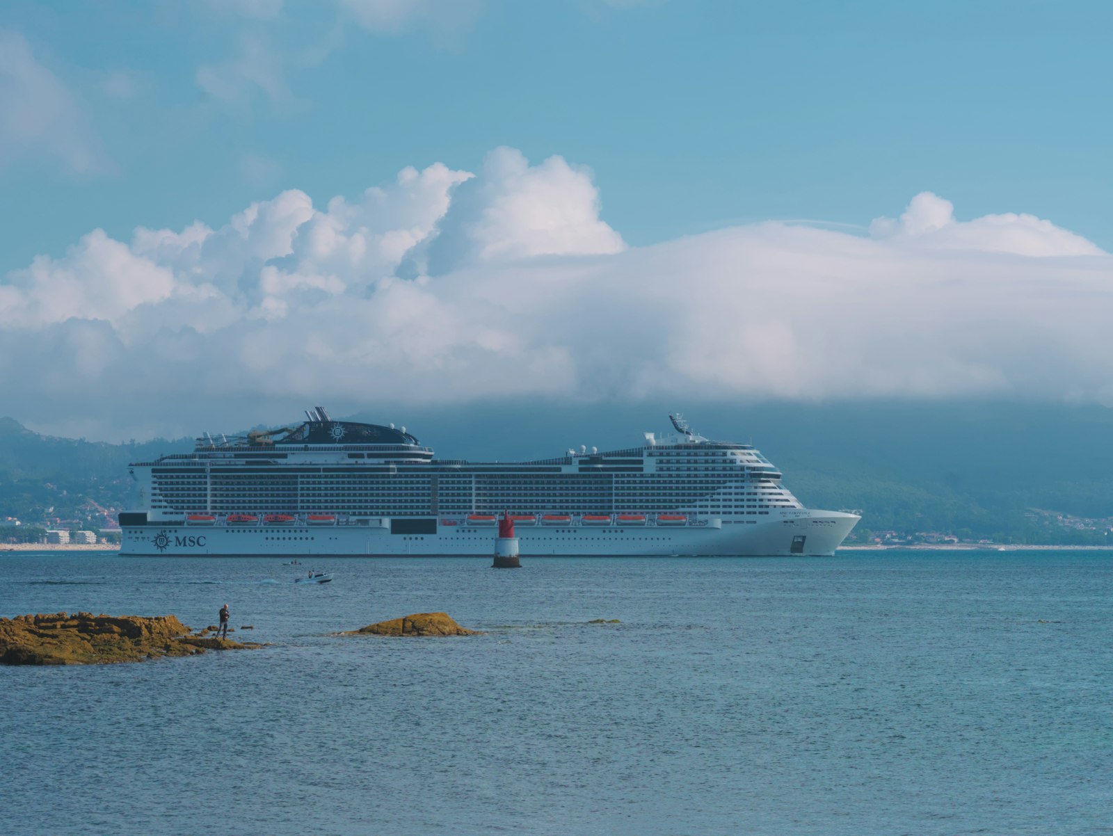 A cruise ship passing a rocky shoreline